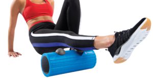 Woman uses foam roller on calves.